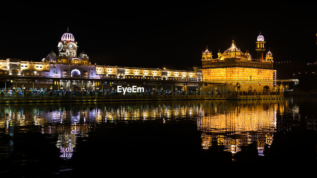 Illuminated golden temple reflecting in lake at night