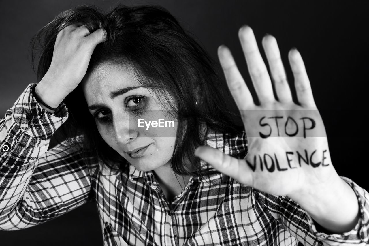 Portrait of woman with hand in hair showing stop violence text on palm