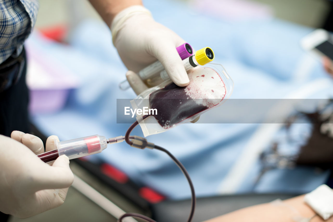 Cropped hand of doctor injecting in blood bag