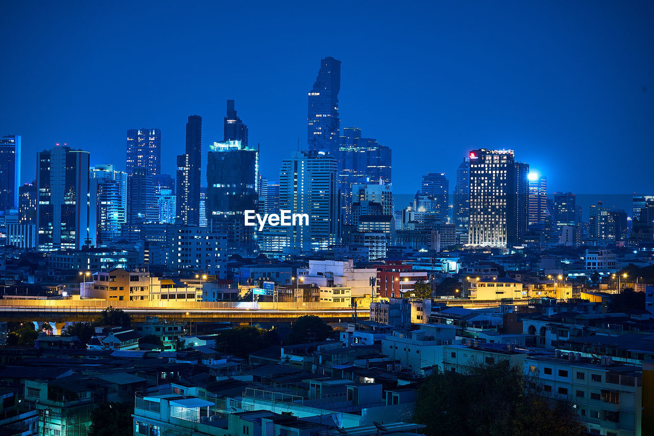 Illuminated modern buildings in city against sky