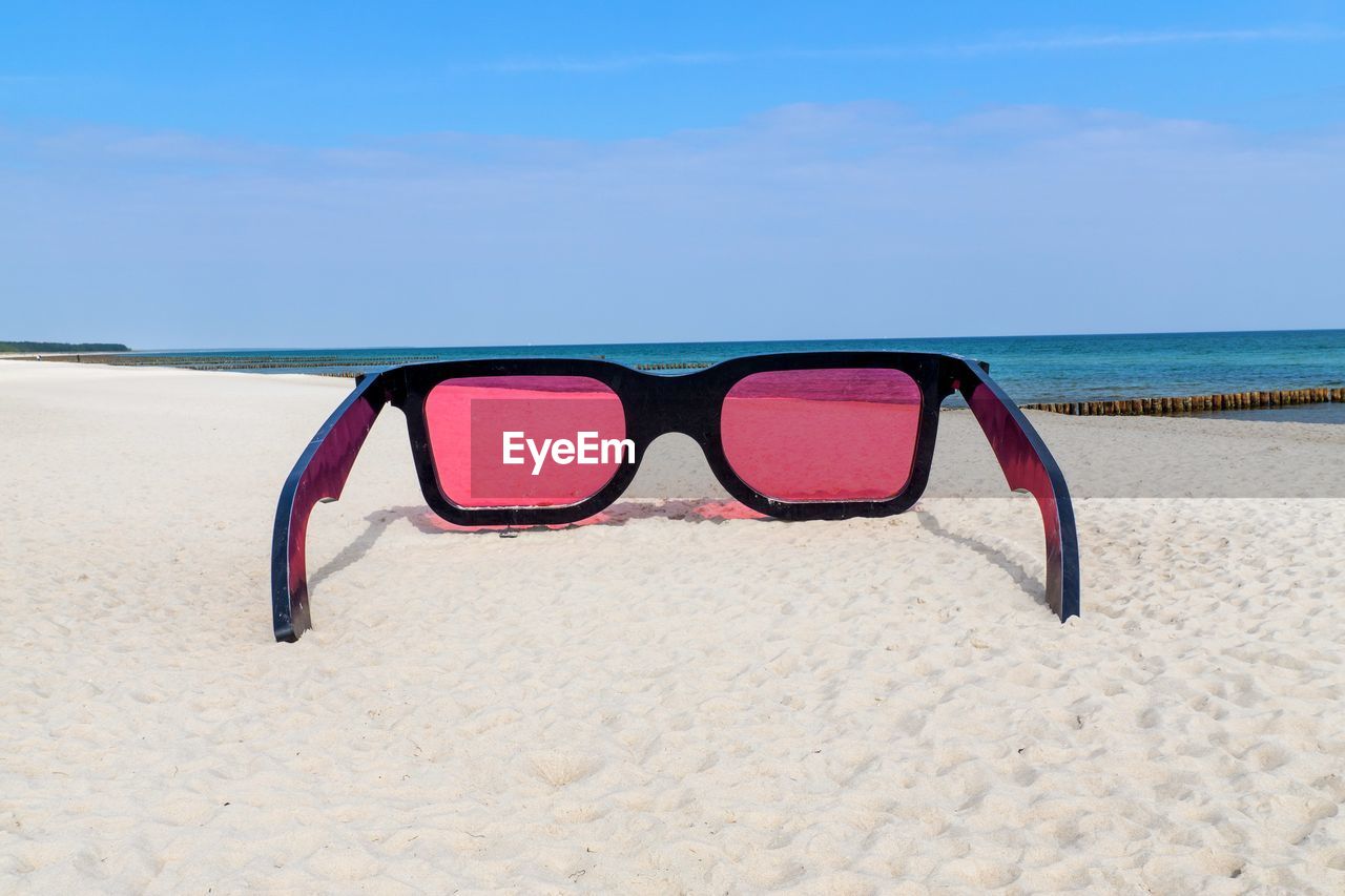 Sunglasses on beach against sky