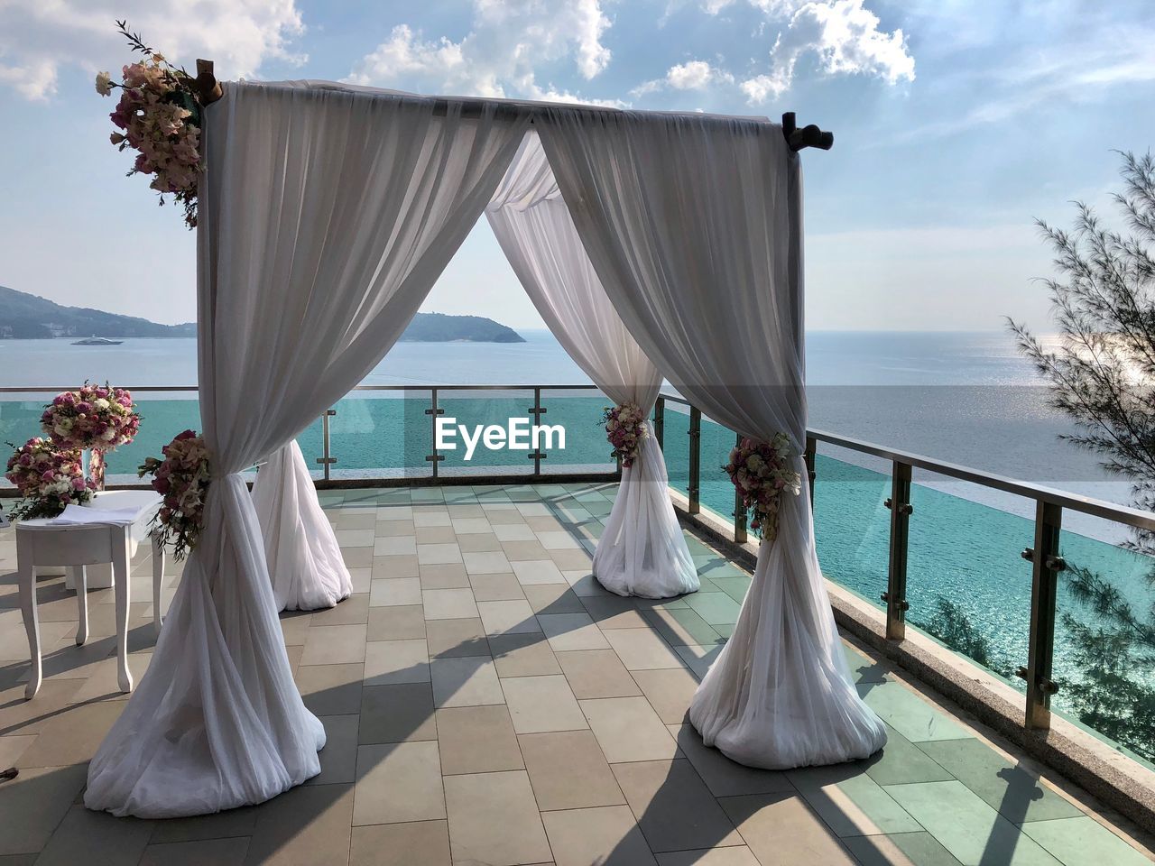 Woman standing on deck chair by sea against sky