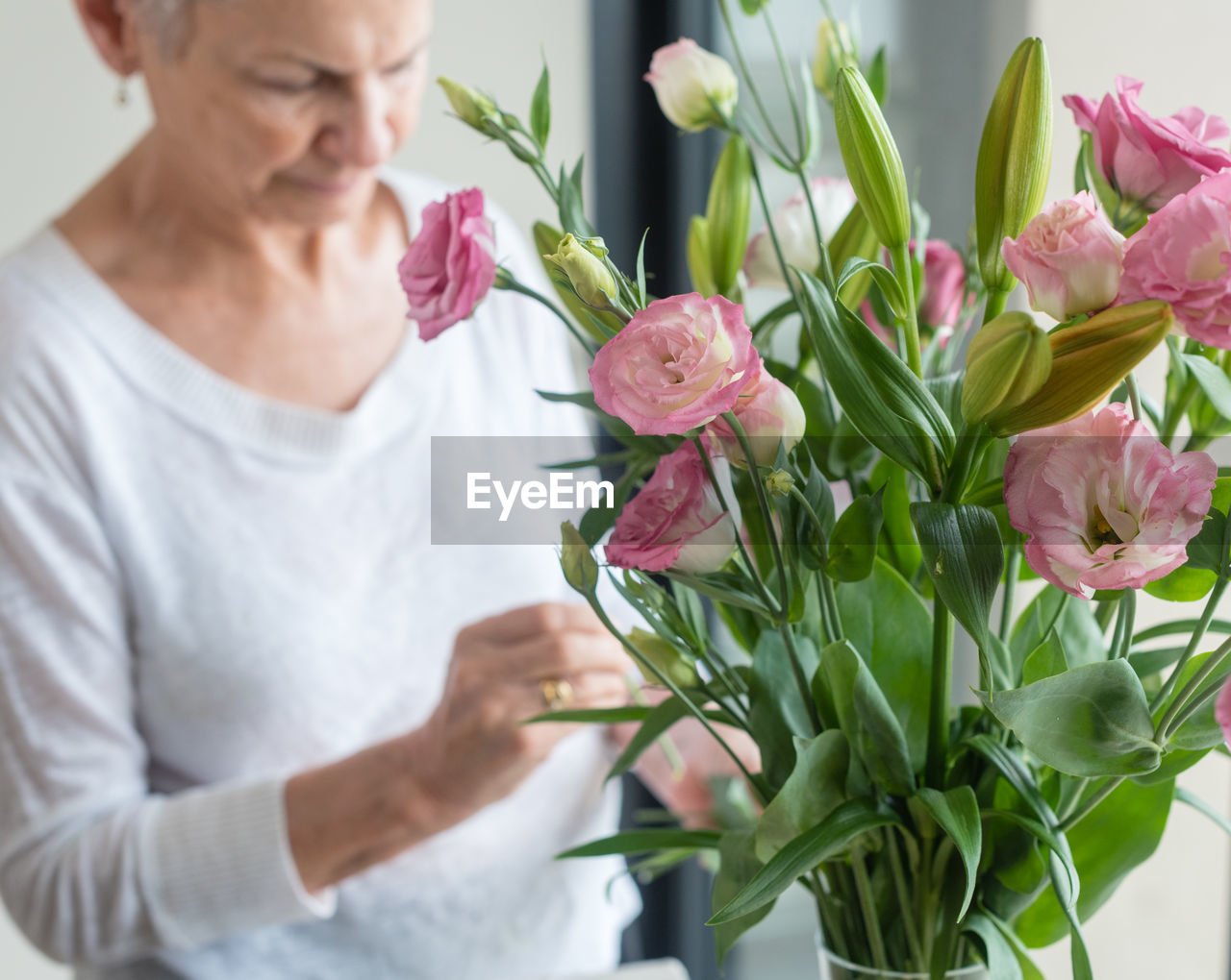 Senior woman standing by flowers