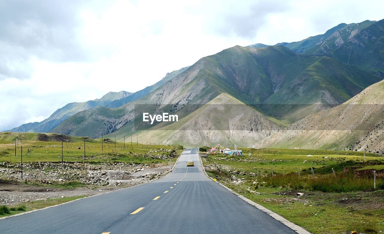 Road leading towards mountains against sky