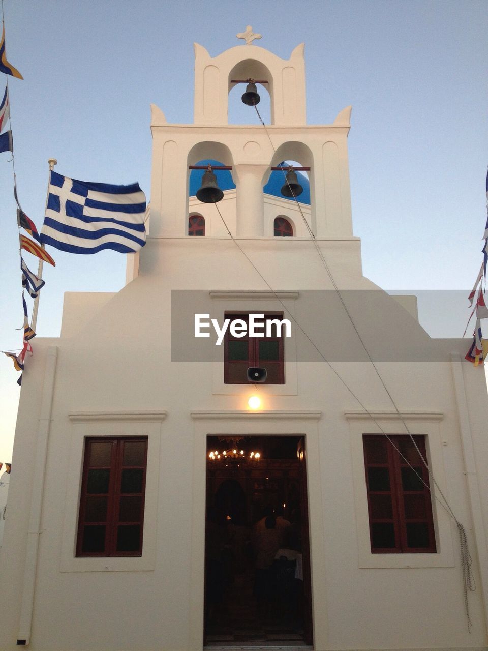 Greek flag on facade of church against blue sky