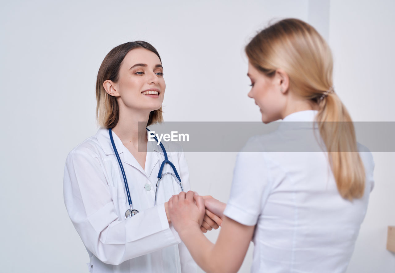 SMILING YOUNG WOMAN STANDING IN FRONT OF TWO WOMEN