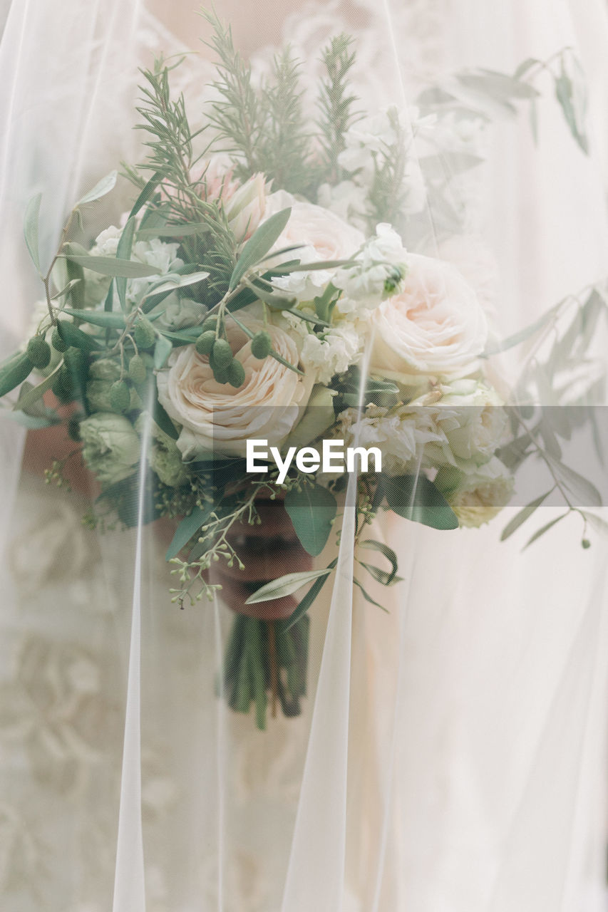 Bride keeping her wedding bouquet under her veil