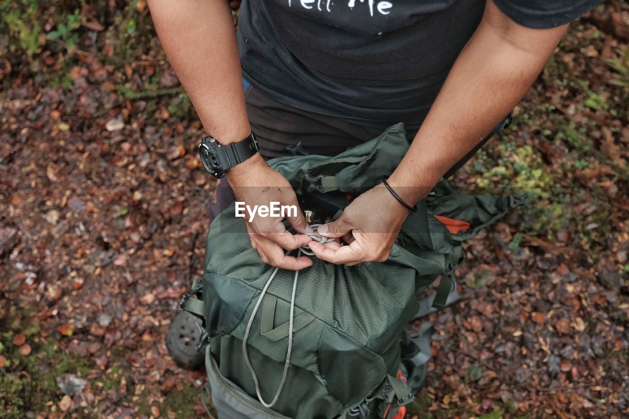 MIDSECTION OF MAN HOLDING AUTUMN LEAVES