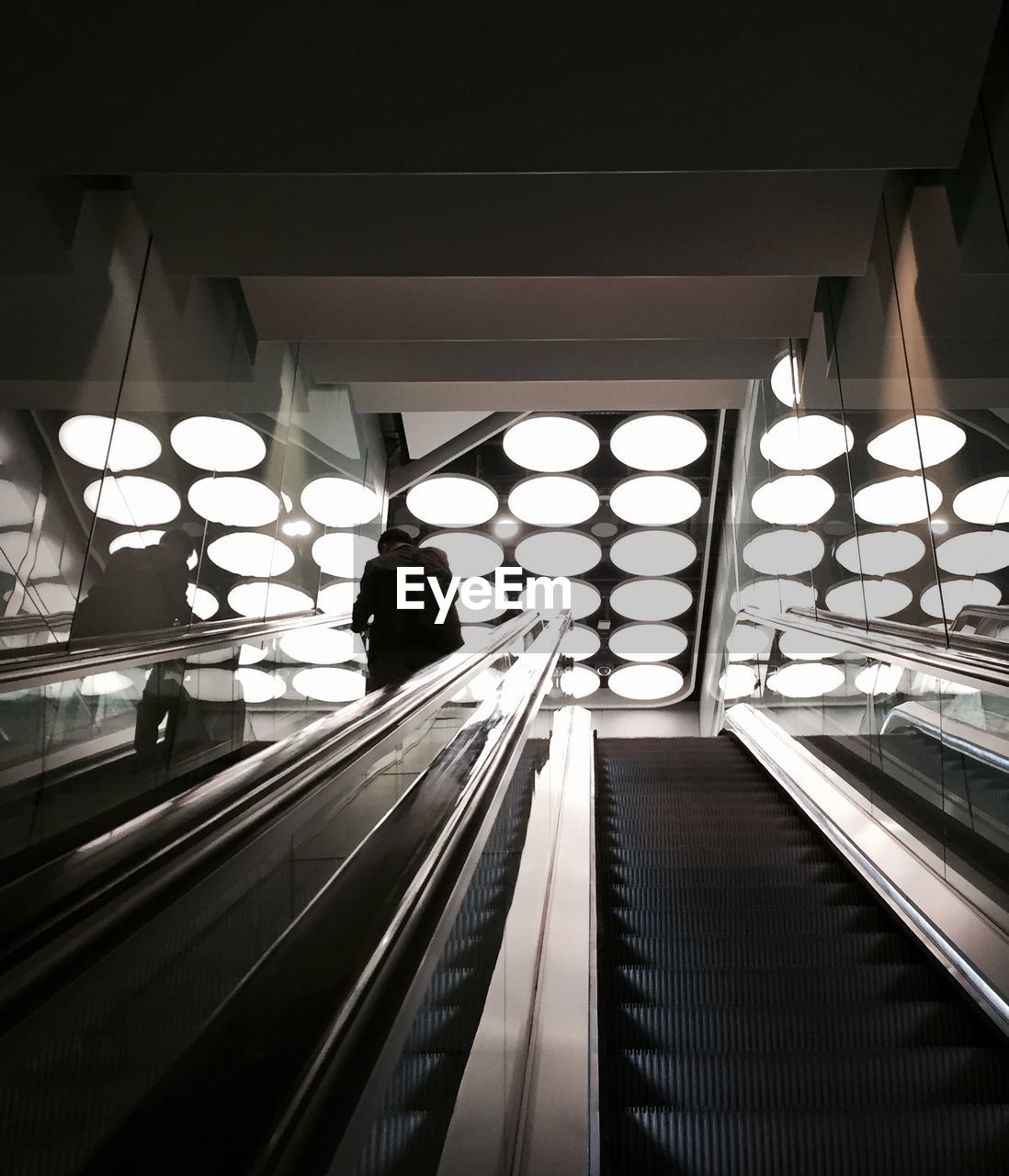 Rear view of silhouette man on escalator in building