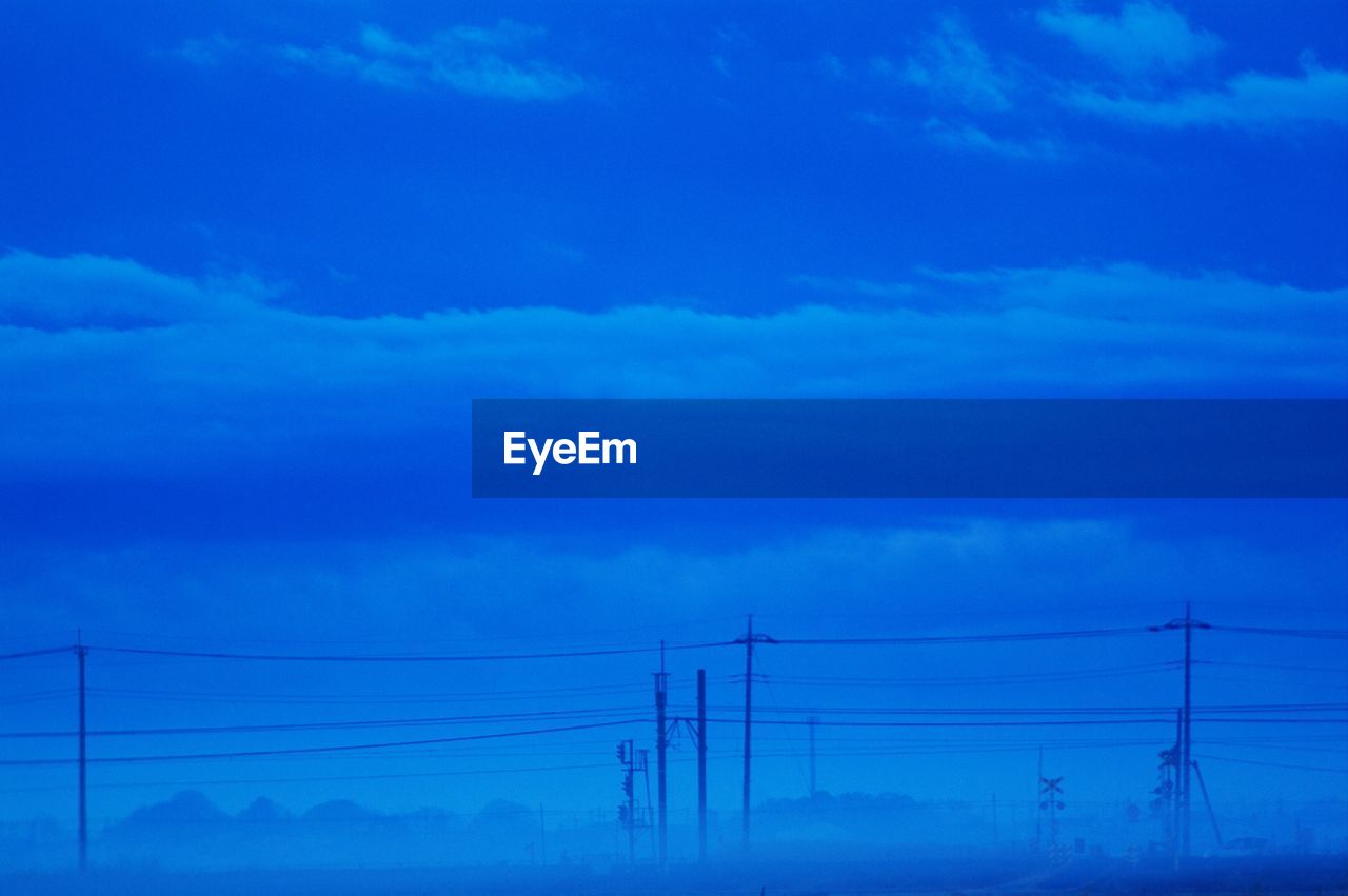 Electricity pylons against blue sky