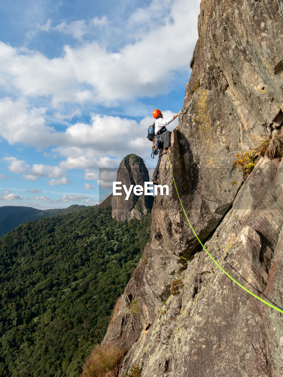 LOW ANGLE VIEW OF PERSON RELAXING ON ROCK