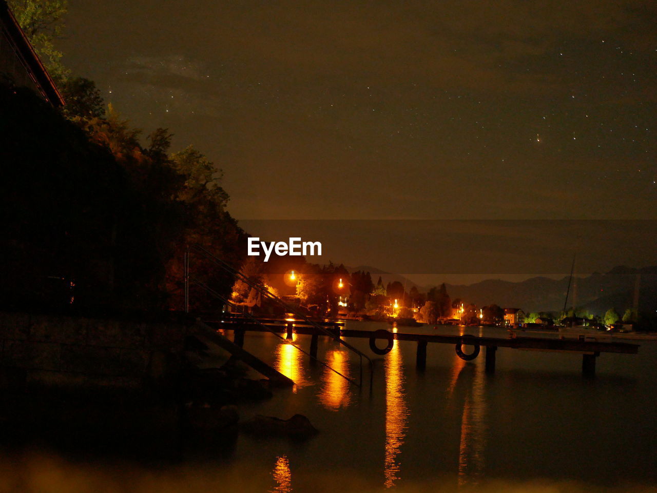 ILLUMINATED BRIDGE OVER RIVER AT NIGHT