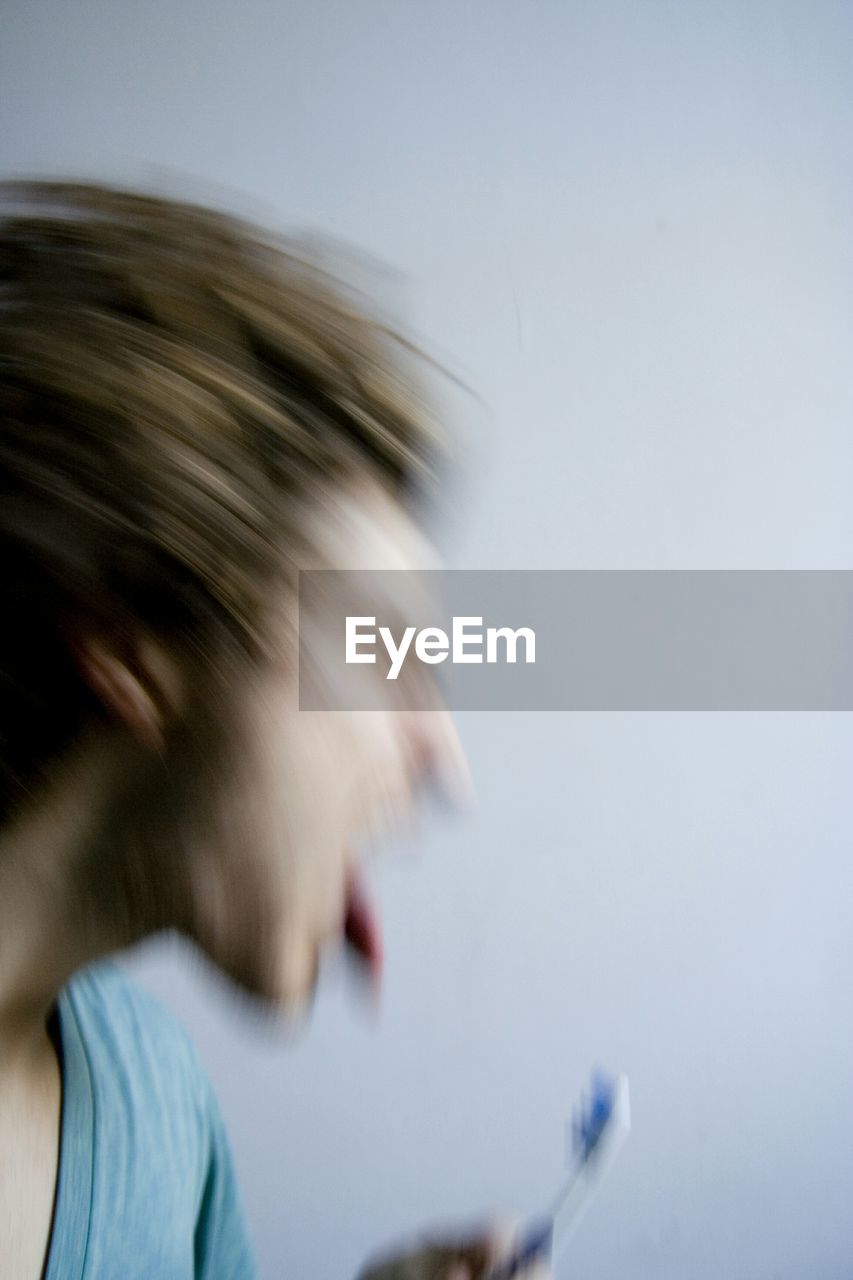 Blurred motion of man brushing teeth at home