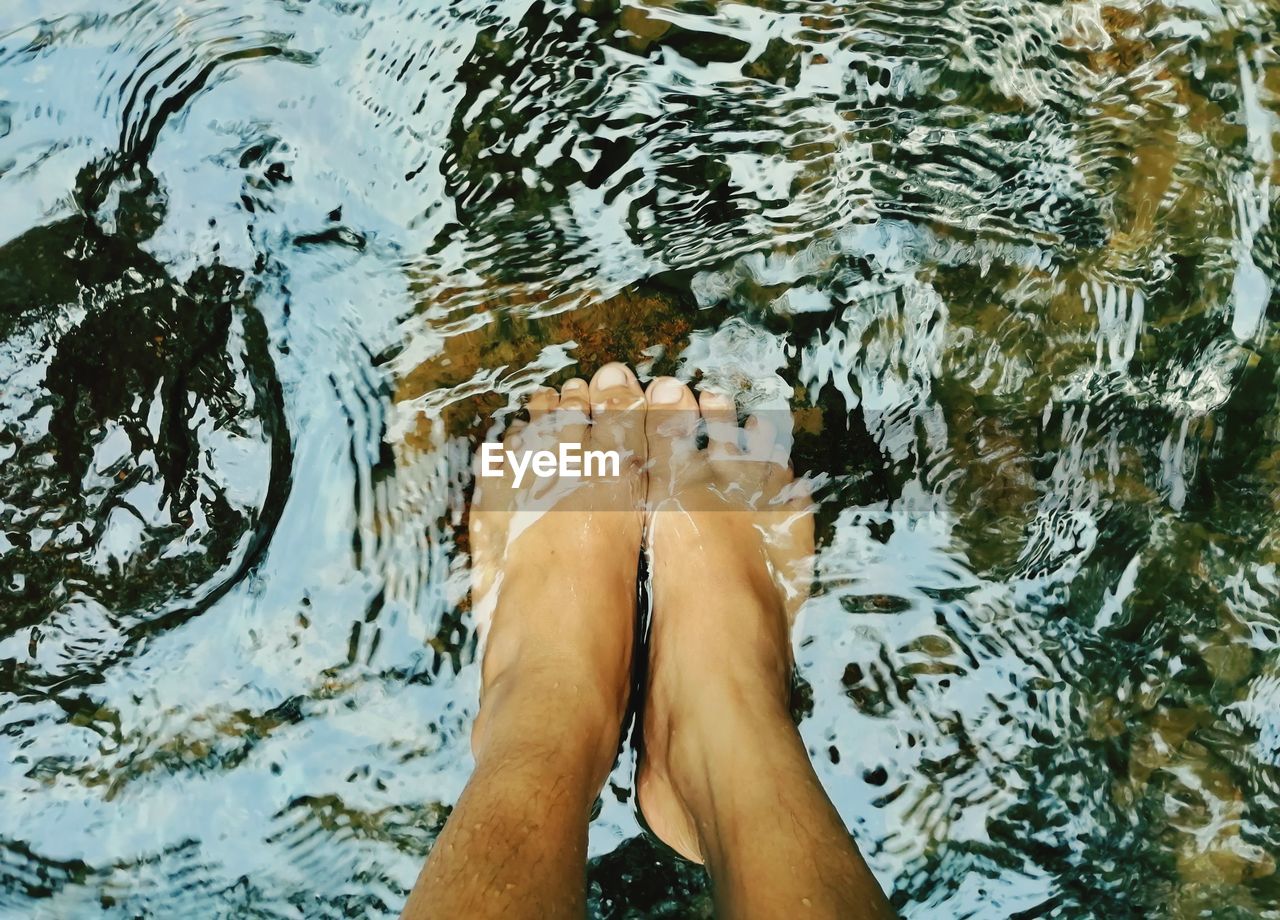 This picture shows a person submerging his feet in very clear water