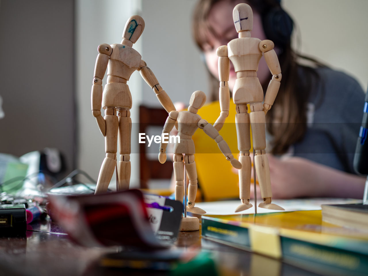 Close-up of wooden figurines with girl in background at home