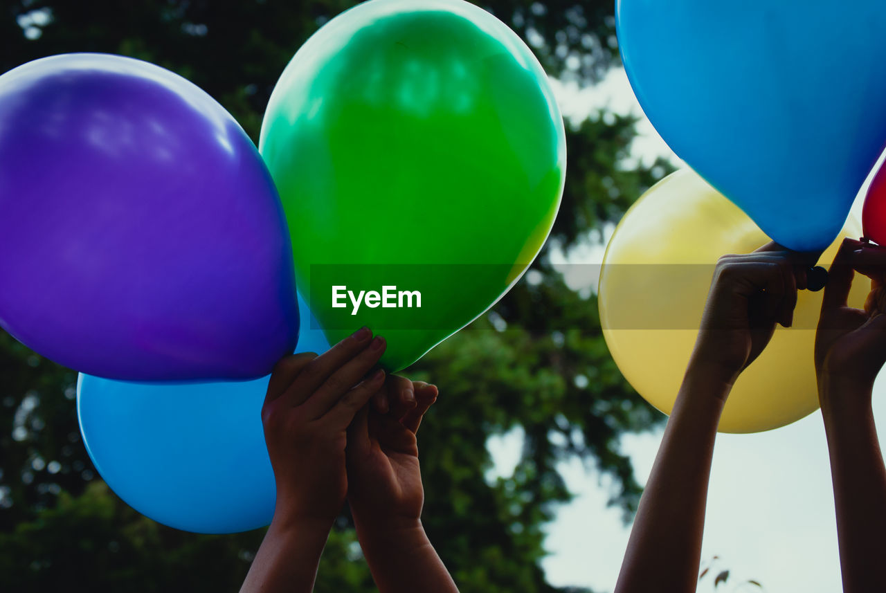 Cropped image of people holding multi colored balloons