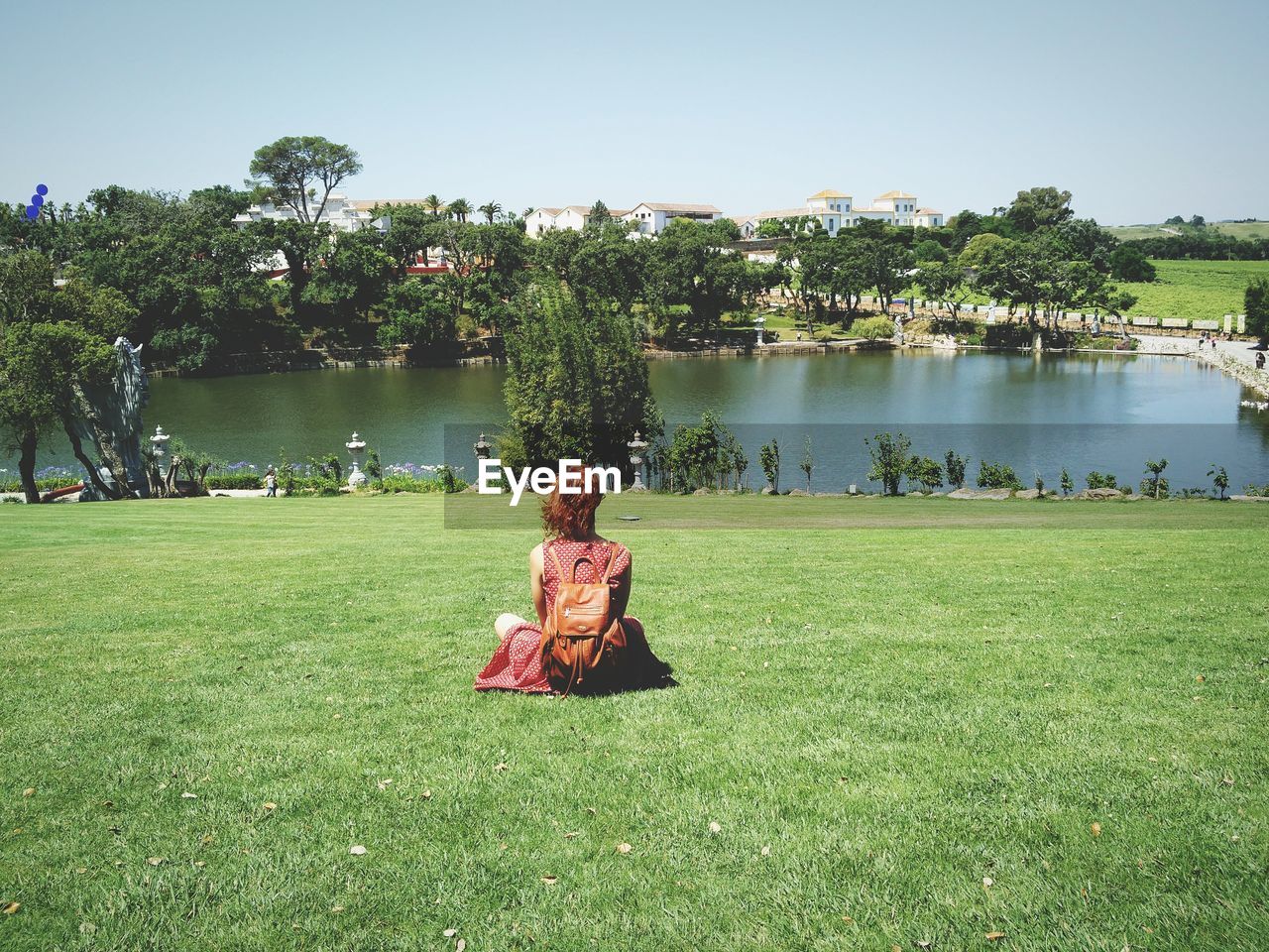 Rear view of woman sitting on grassy field at buddha eden garden