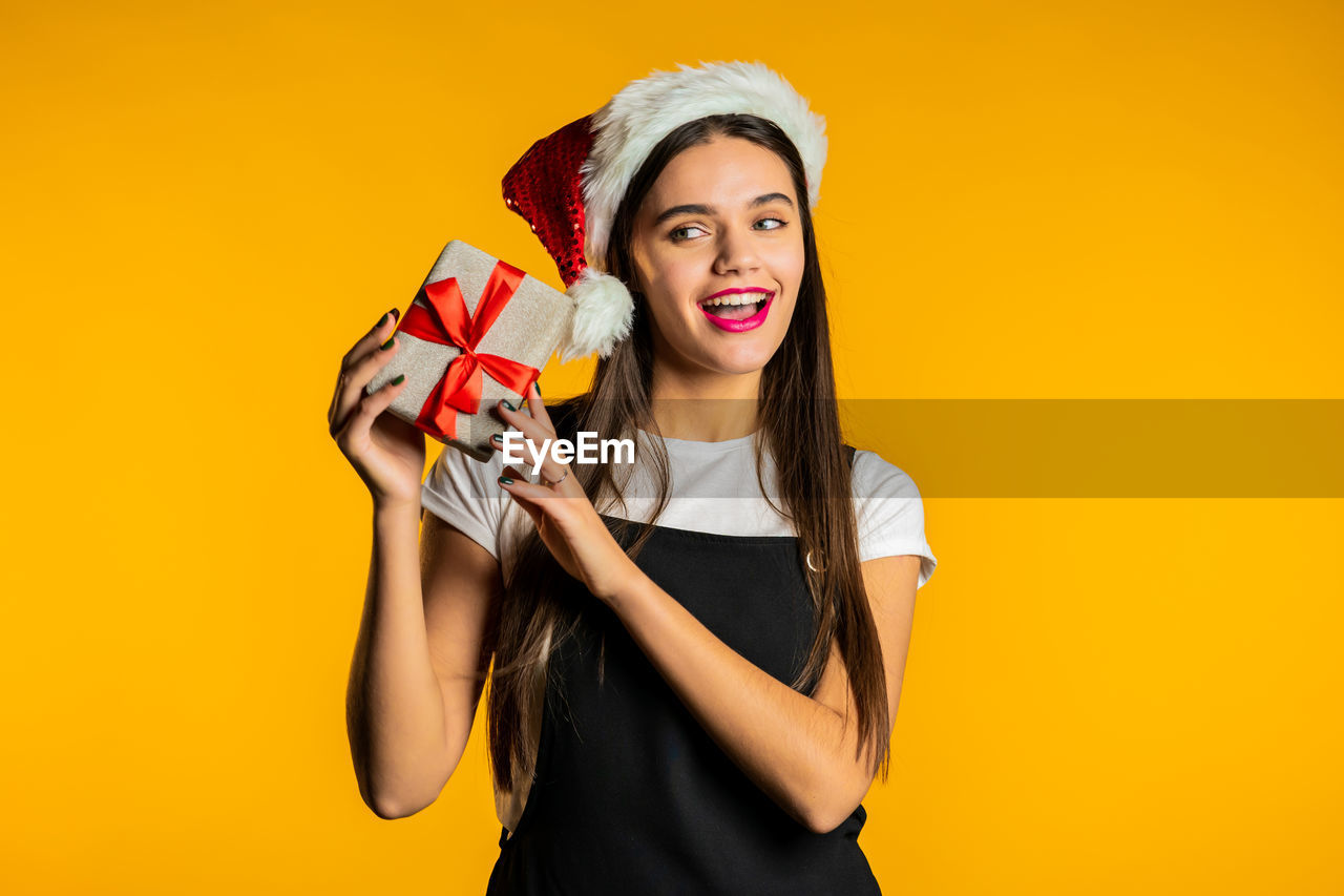 PORTRAIT OF A SMILING YOUNG WOMAN AGAINST YELLOW GRAY BACKGROUND