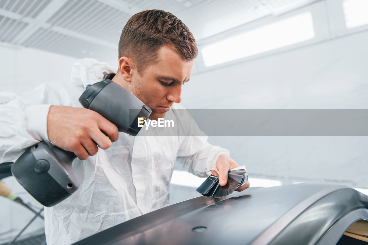 Painting the car. man in uniform is working in the auto service.