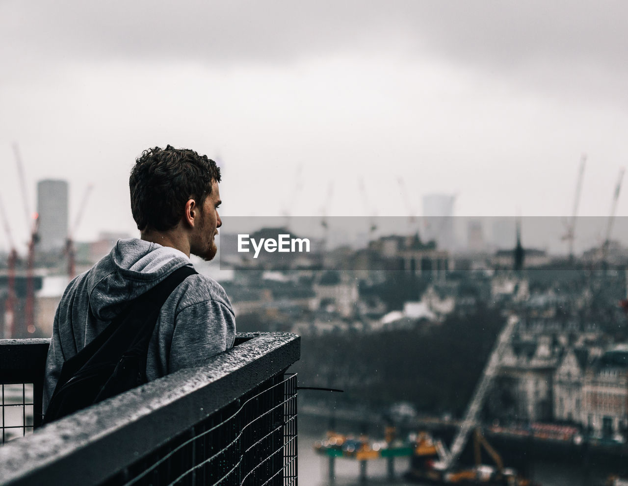 Young man looking at cityscape against sky