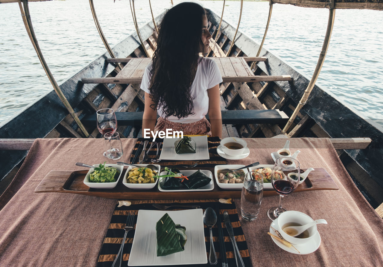 Woman standing by food on table in boat