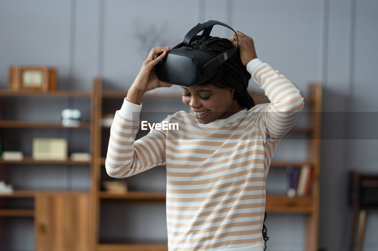 Inspired afro woman at home put on vr helmet to enjoy virtual reality online game cyber simulation
