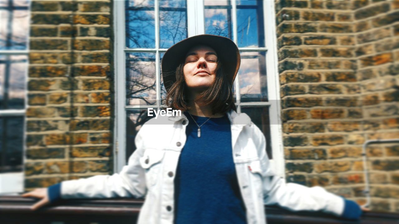 Young woman wearing hat against building