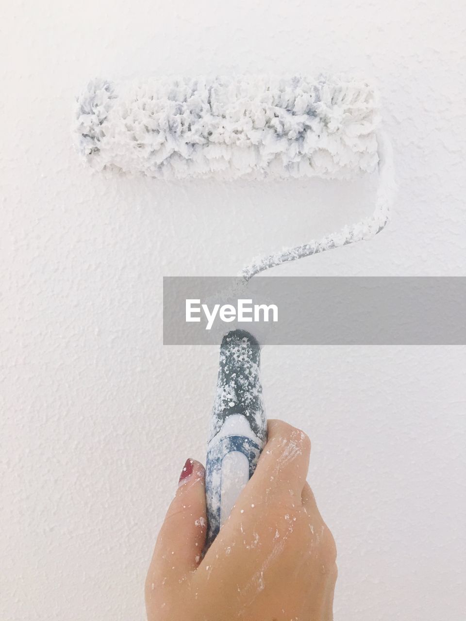 Close-up of woman painting wall with paint roller