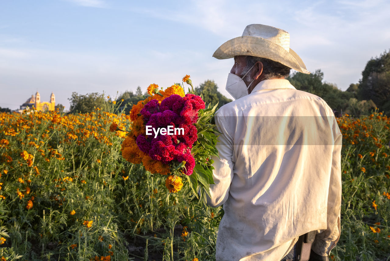 Mexican farmer carrying orange and cherry cempasuchil flowers