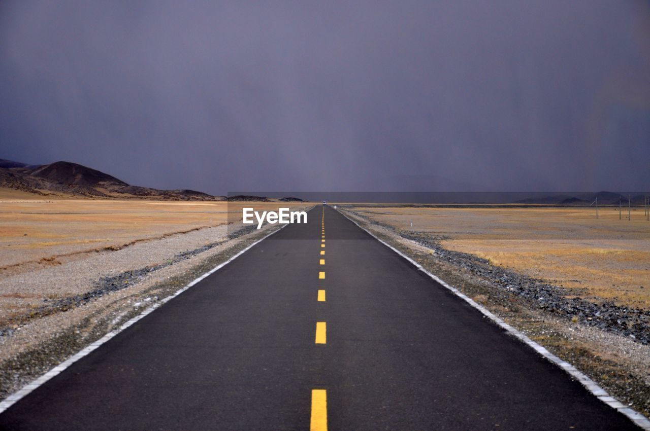 Empty road amidst landscape against sky