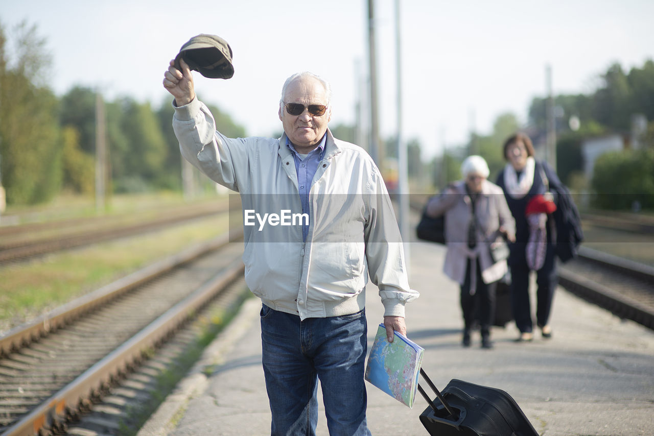 Portrait of senior elderly man holding hat and map,waiting  train traveling journey during pandemic