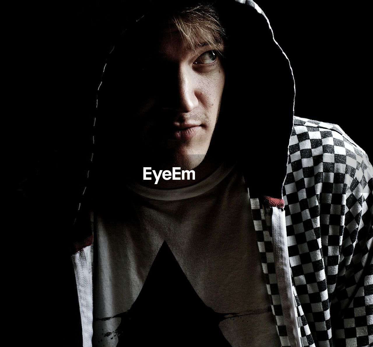 Close-up of young man wearing hooded jacket in darkroom