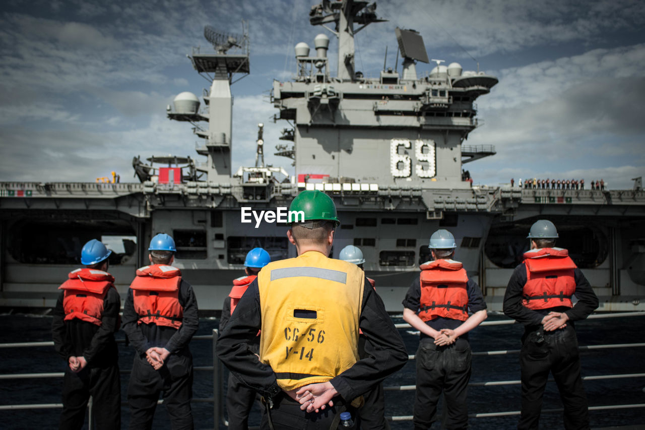 Rear view of us navy soldiers standing against ship