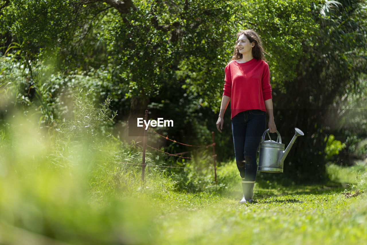 Woman walking in vegetable garden holding watering can