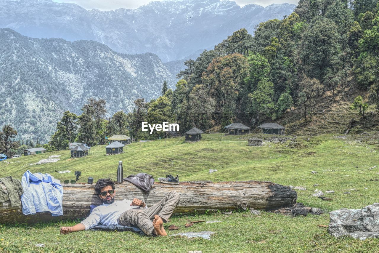 Man relaxing on land against mountains
