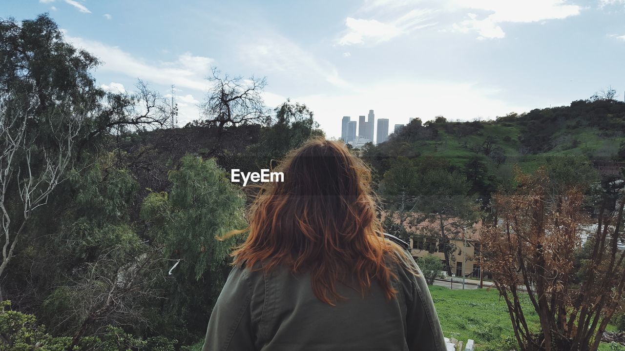 Rear view of woman standing at park against sky