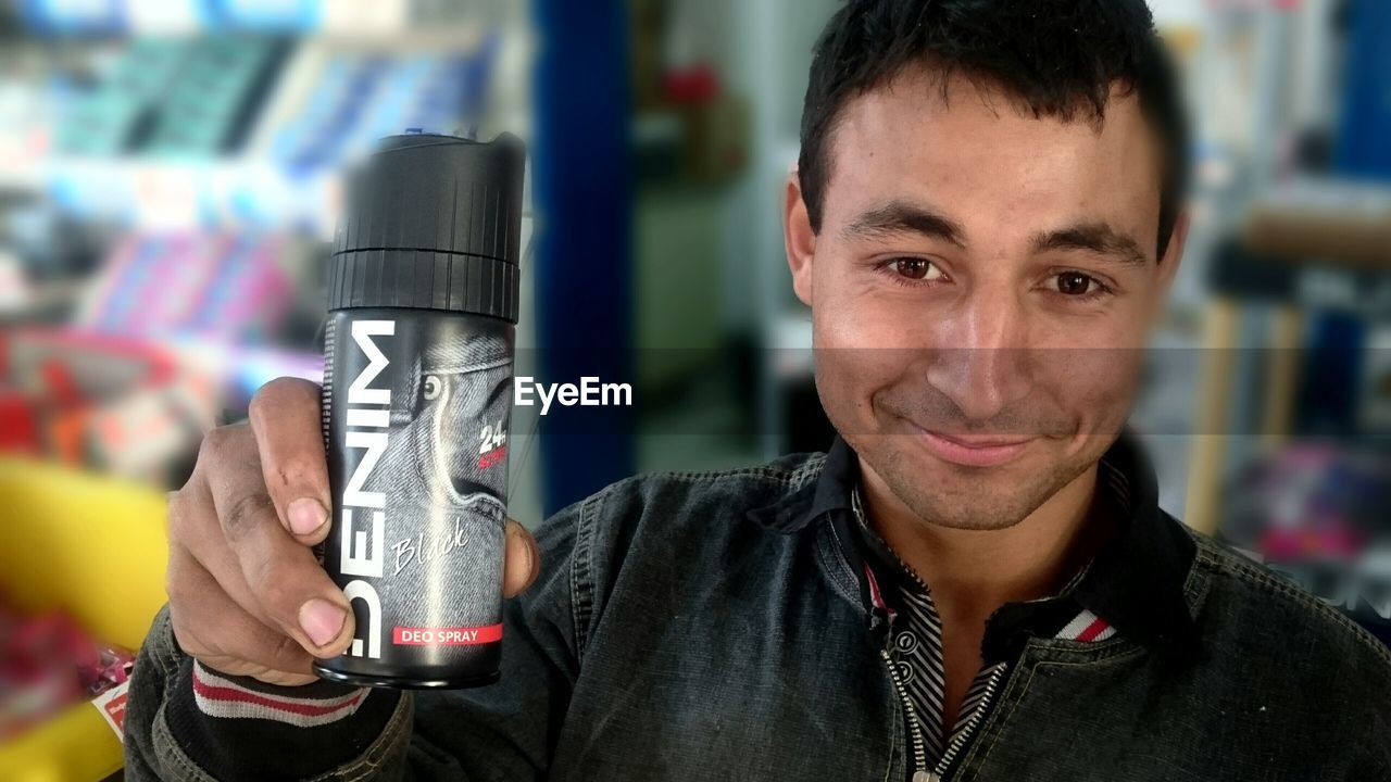 Close-up portrait of man holding perfume bottle in store