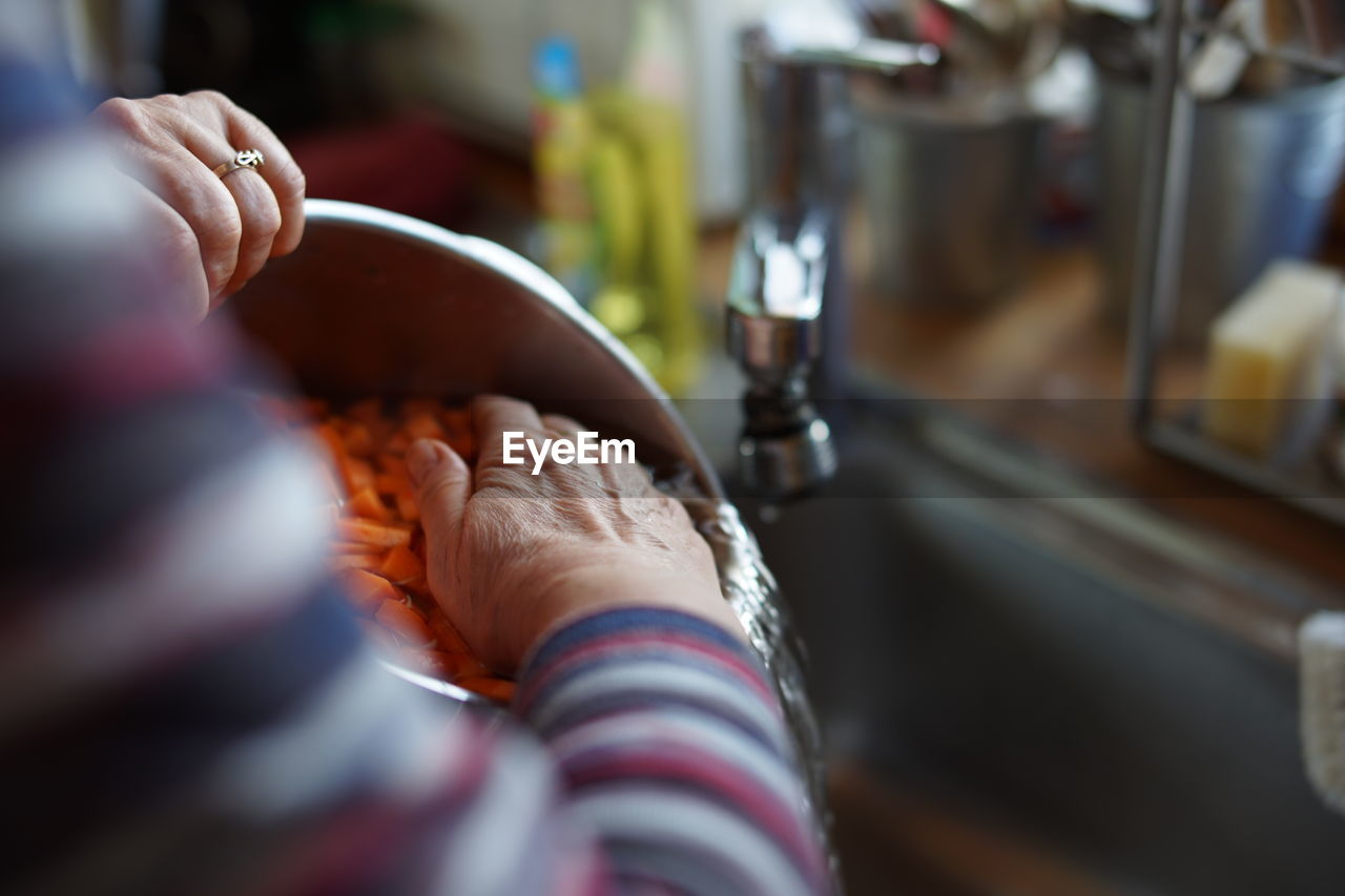 Close-up of woman washing sliced carrots