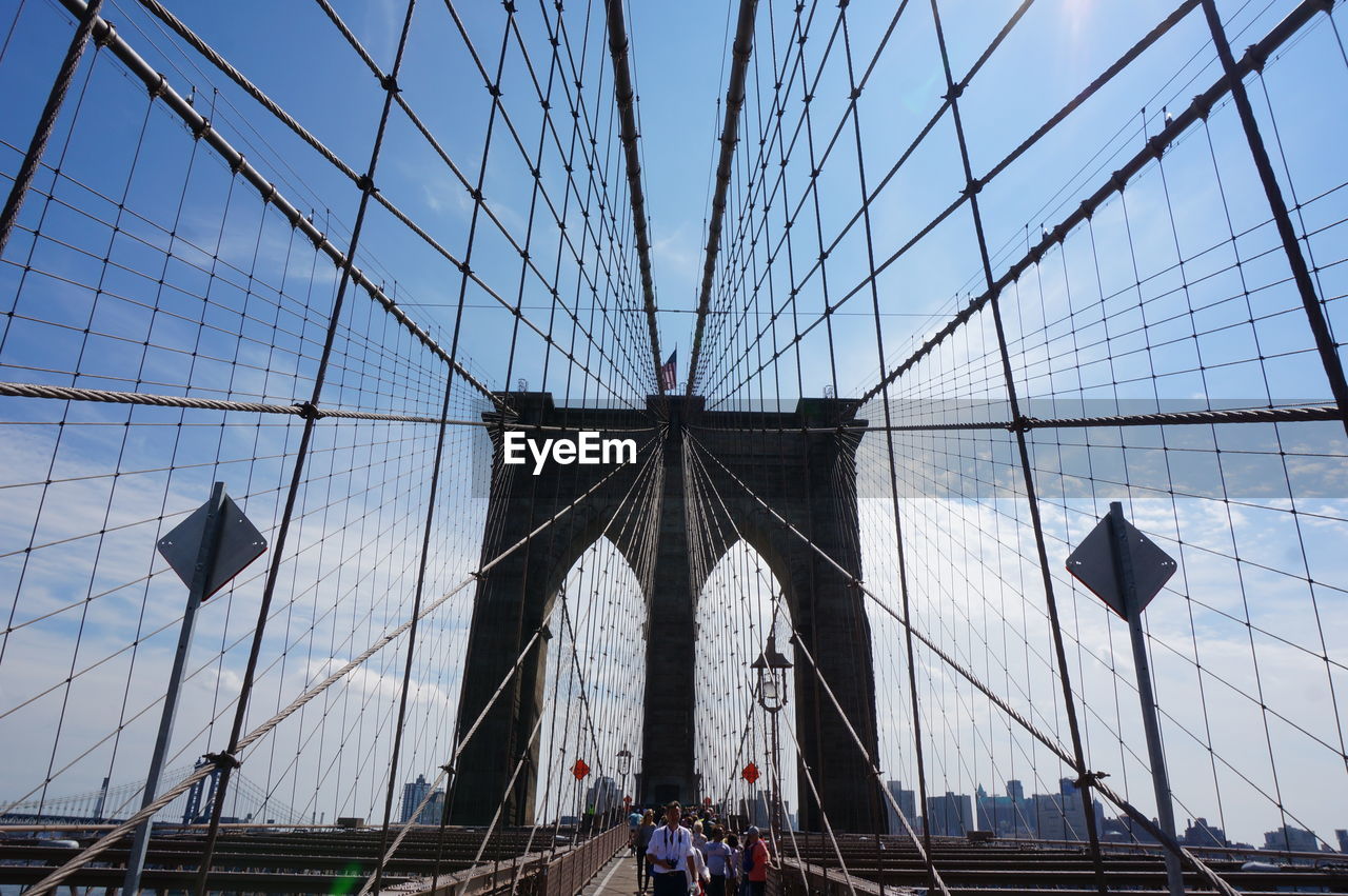 LOW ANGLE VIEW OF SUSPENSION BRIDGE AGAINST CLOUDY SKY