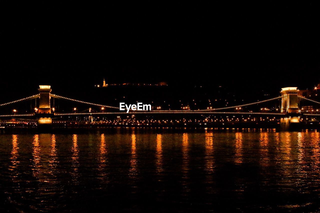 Illuminated bridge over river at night