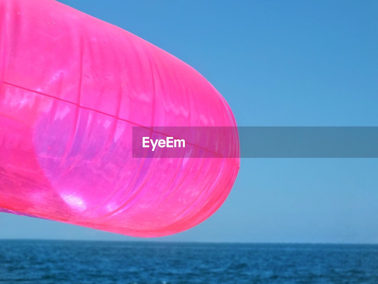 Scenic view of pink round sea against clear blue sky