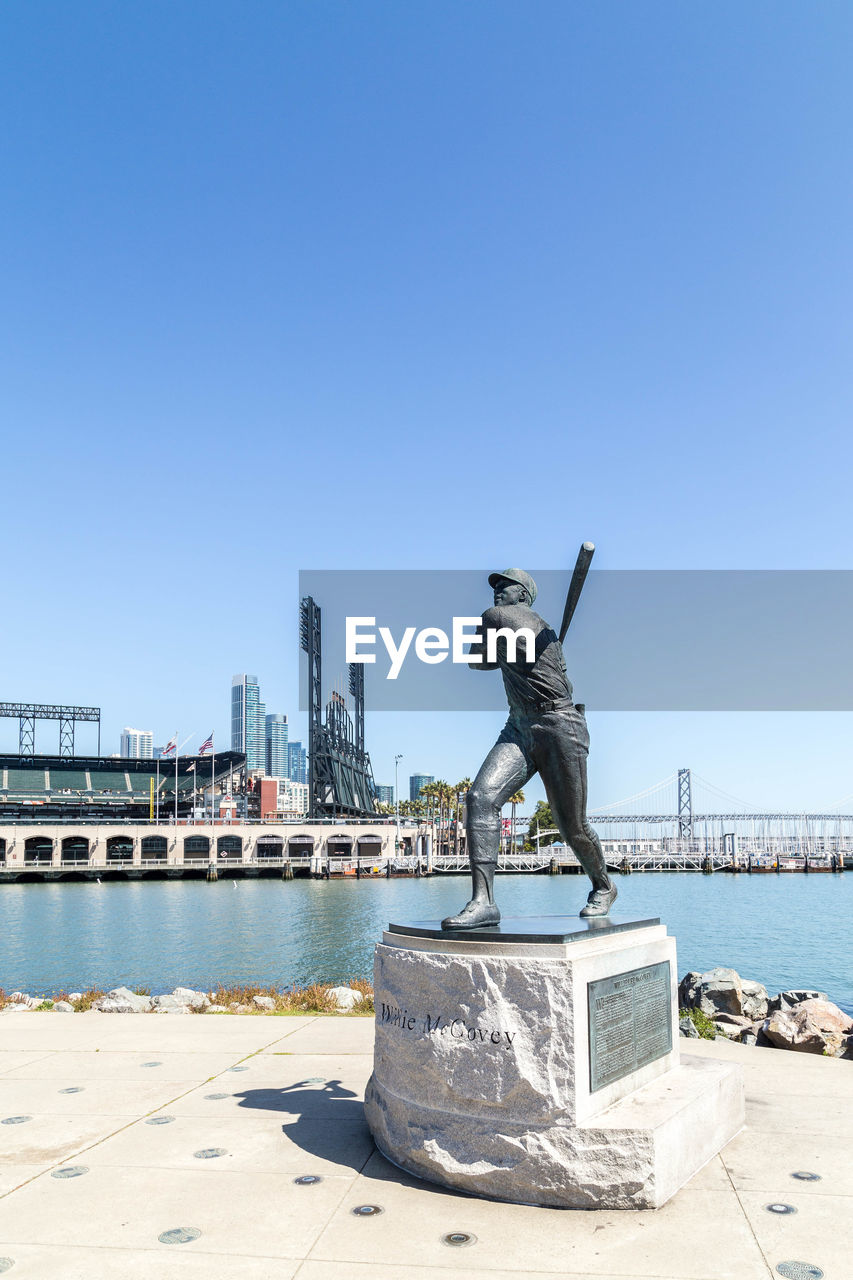 STATUE BY SEA AGAINST CLEAR SKY IN CITY