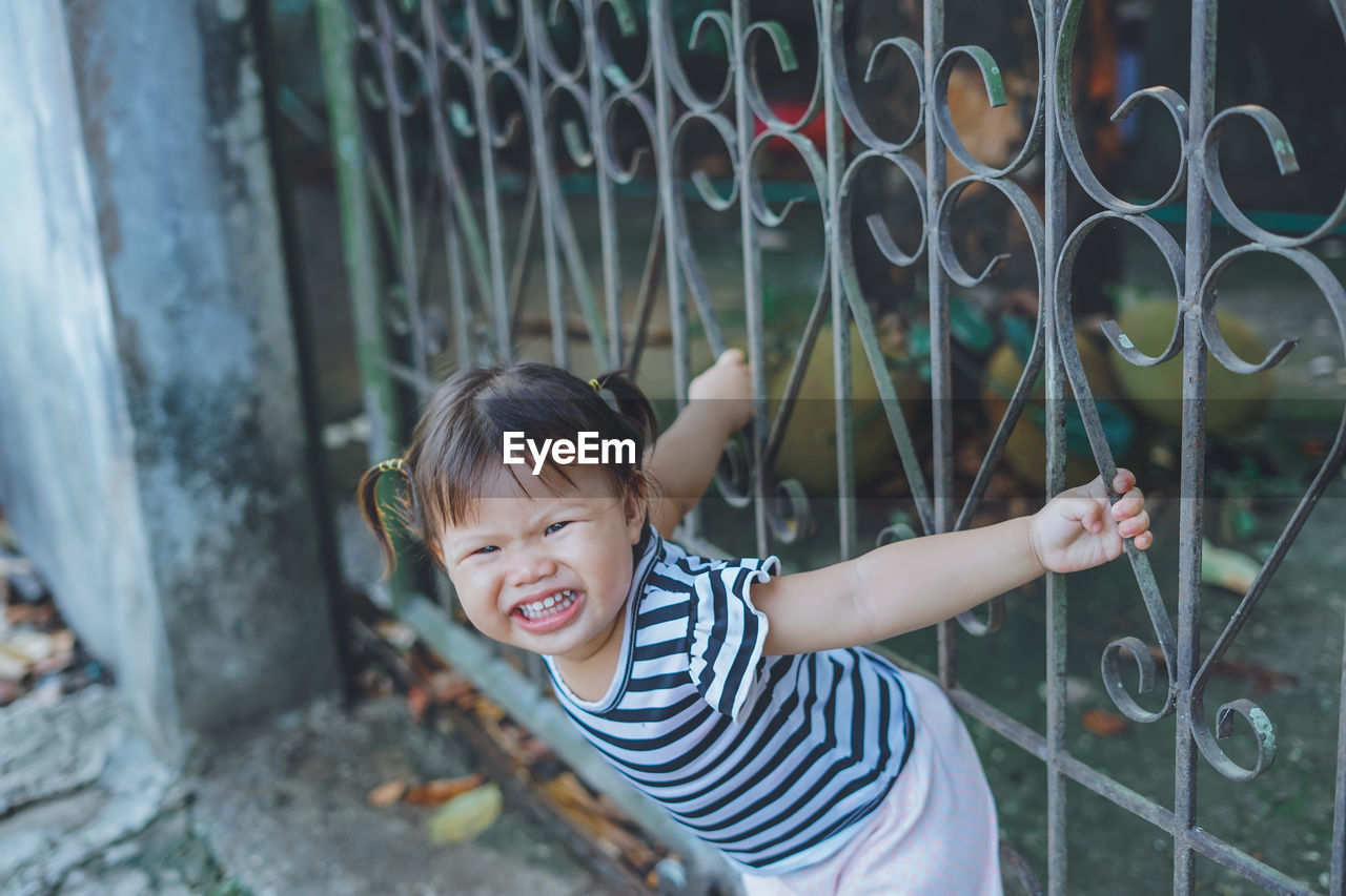 Portrait of cute girl playing on gate