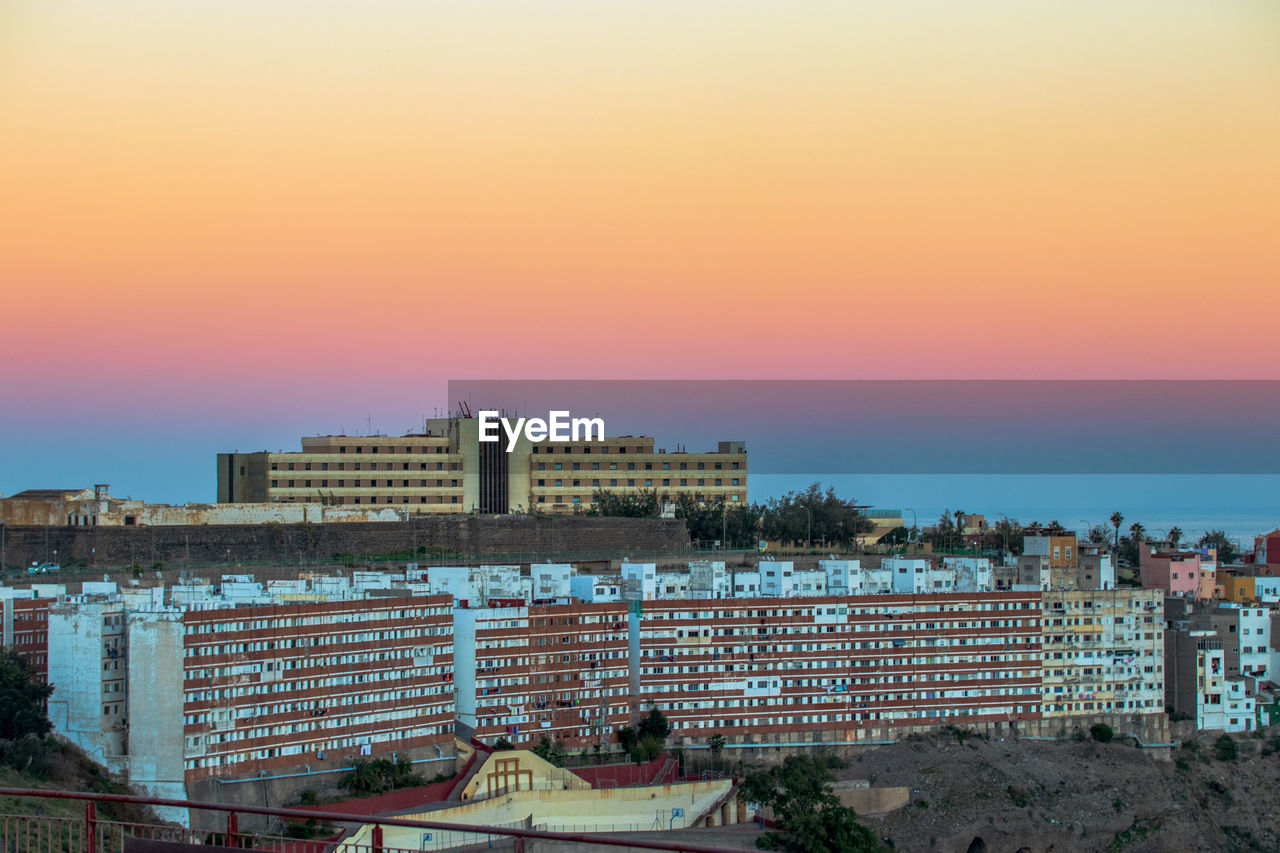 HIGH ANGLE VIEW OF BUILDINGS AGAINST SKY DURING SUNSET