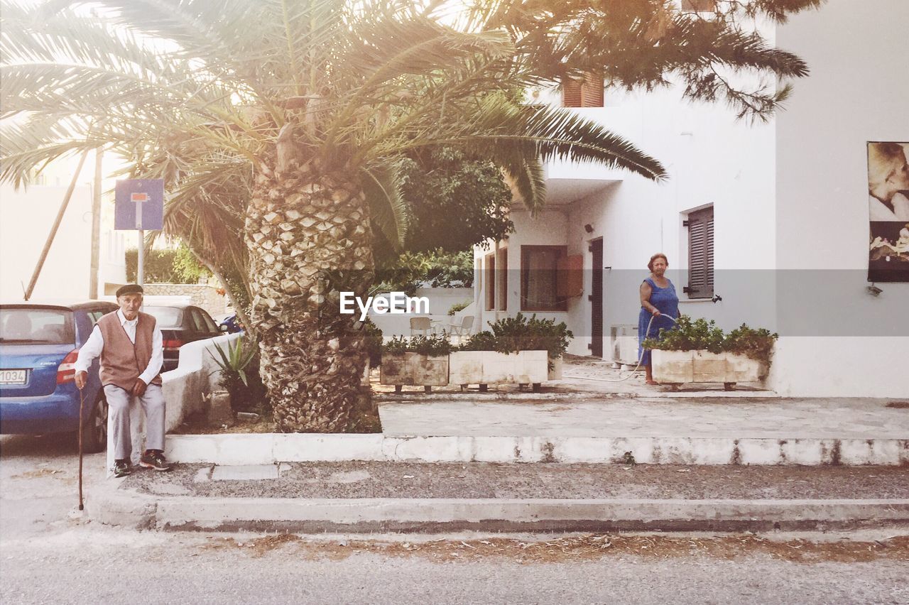 MAN STANDING ON STEPS BY PALM TREE