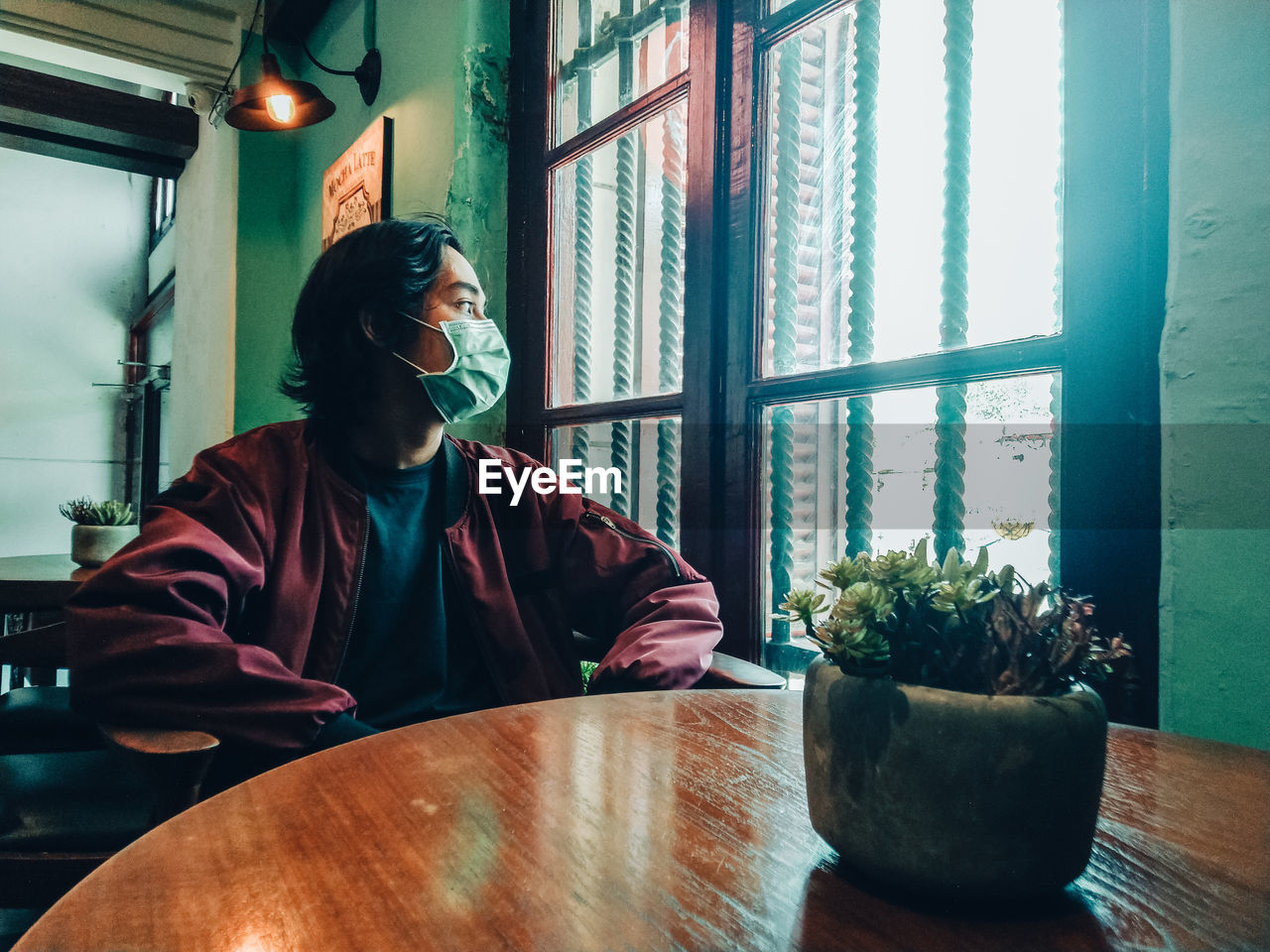 Young man looking through window at home