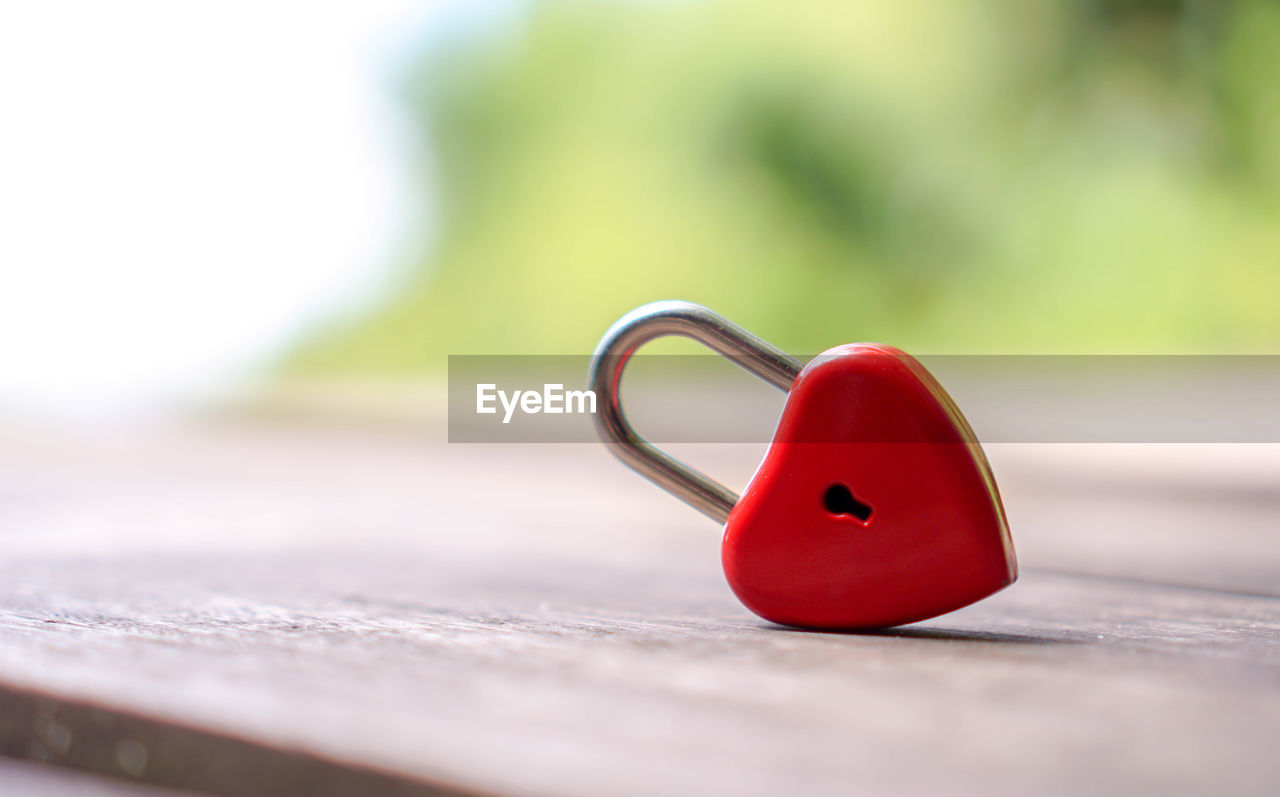 Close-up of red heart shaped padlock on table