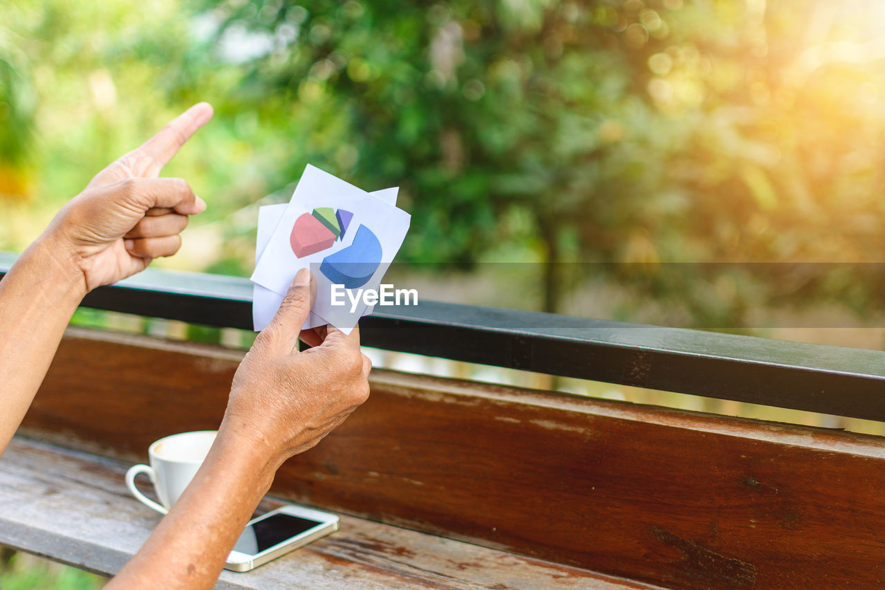 Cropped image of woman pointing while holding graphs at table