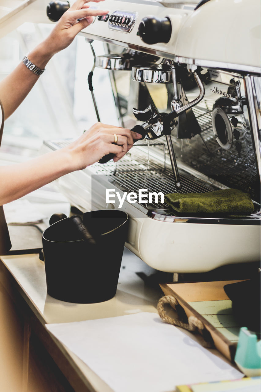 Cropped hands of woman using coffee machine