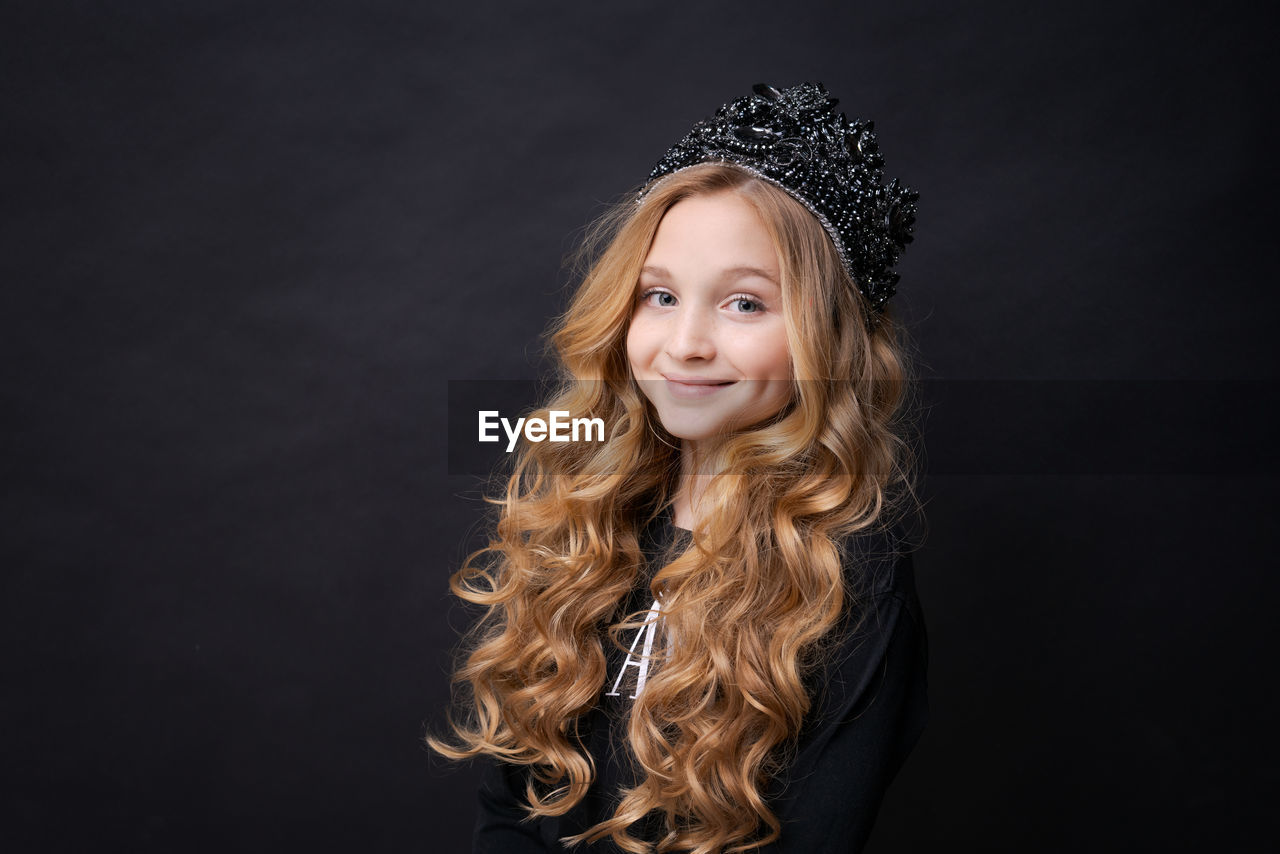 Adorable happy smiling little girl in princess crown celebrating on black